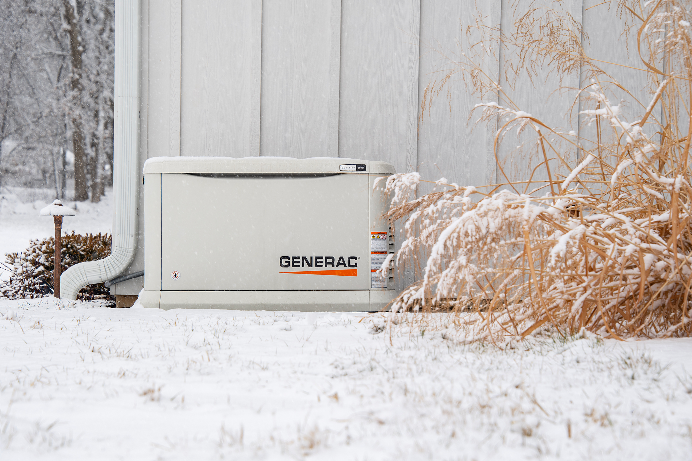 A Generac standby generator in the show outside of a home.