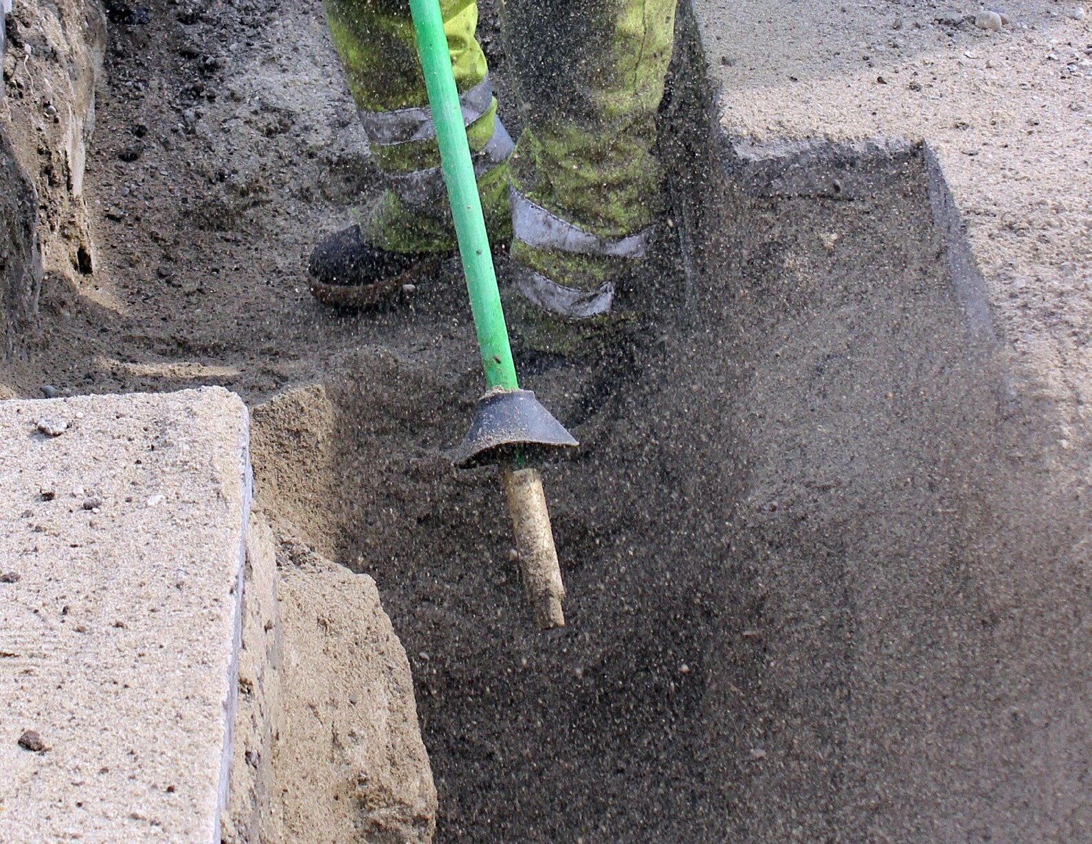 Technician using air spade for precision trench excavation in soil.
