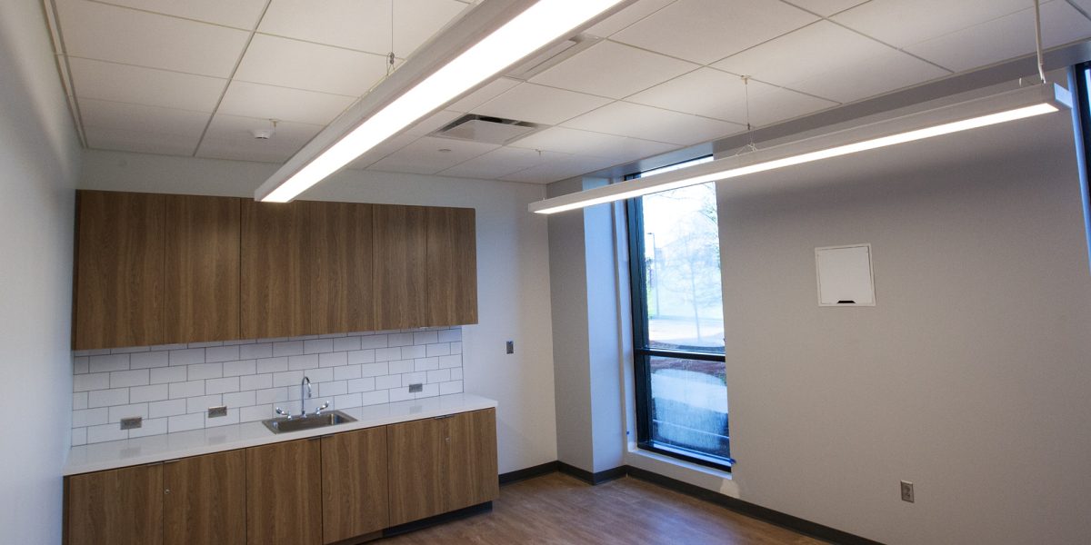Suspended linear LED task lighting and power outlets for a staff breakroom at NCSSM Morganton by Fountain Electric.